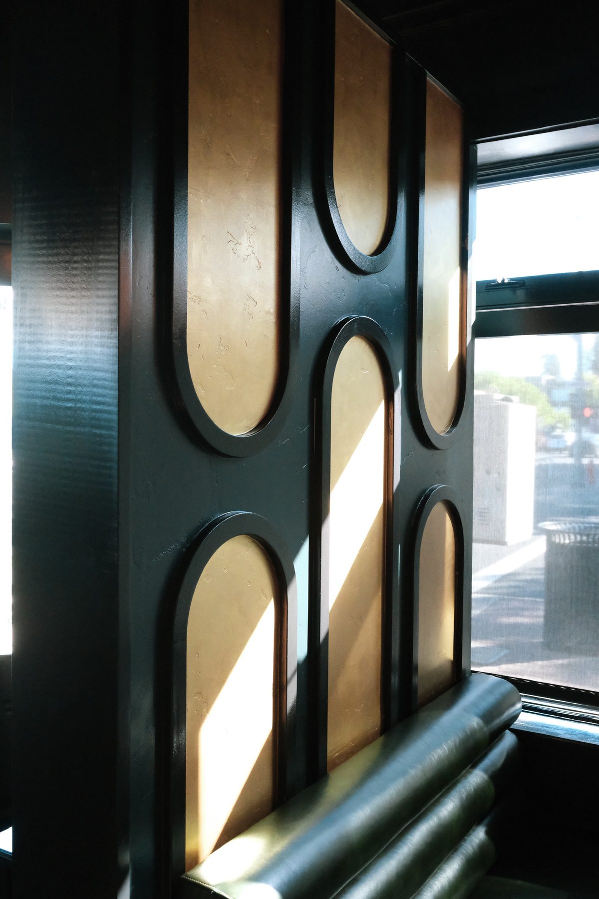 Brass arch paneling and a leather banquette by the window