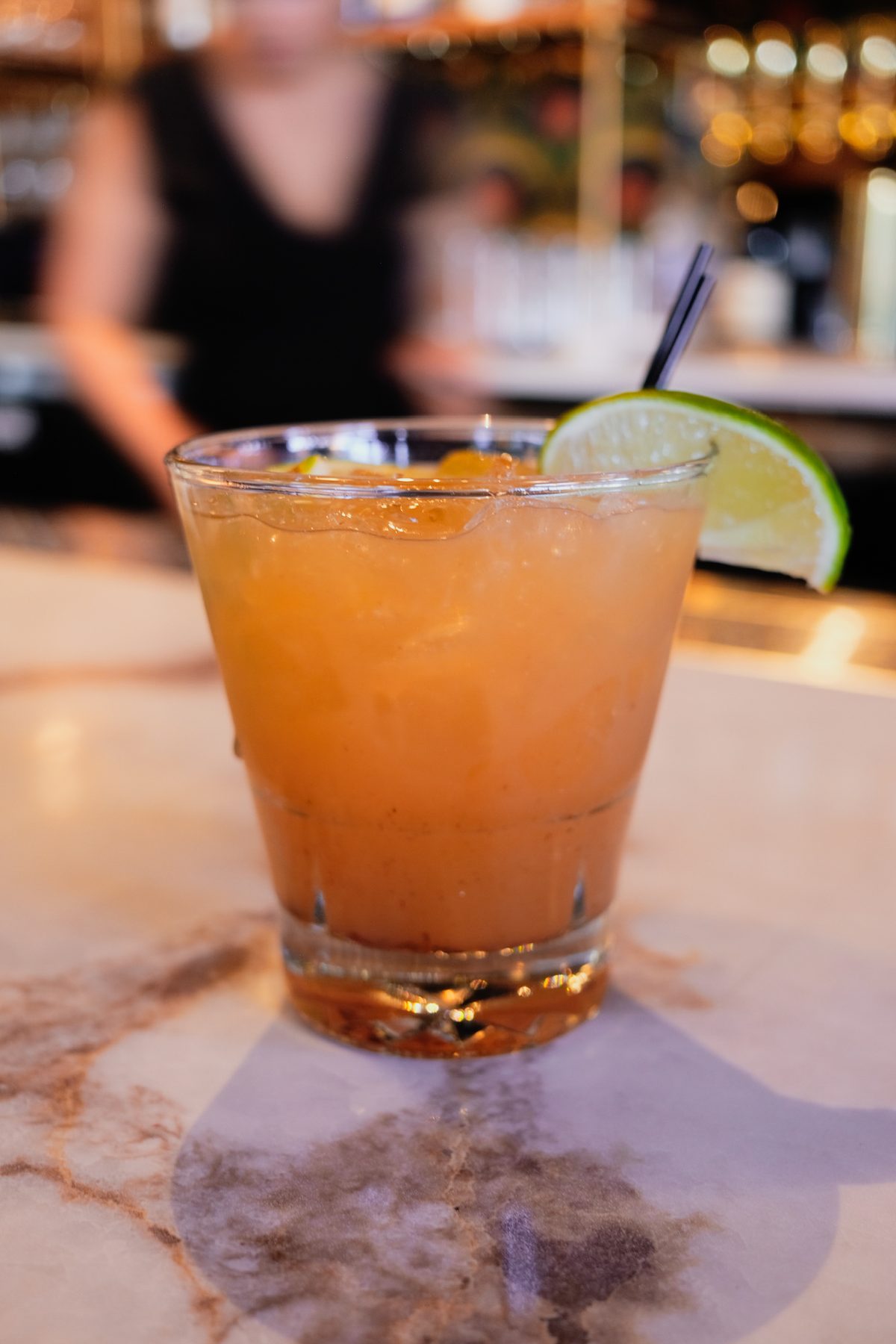 A citrus cocktail over crushed ice with a lime wheel